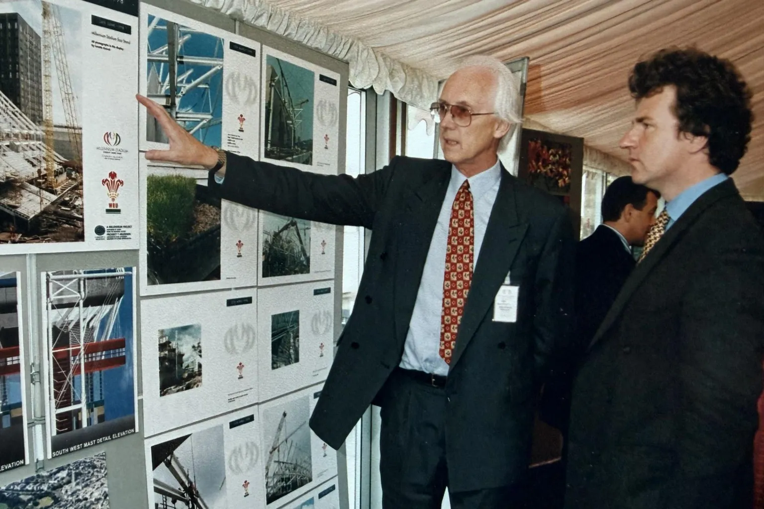 Pat Thompson Archive Suited with collar and tie, Pat stands before a display board showing plans for the stadium to Peter Ainsworth