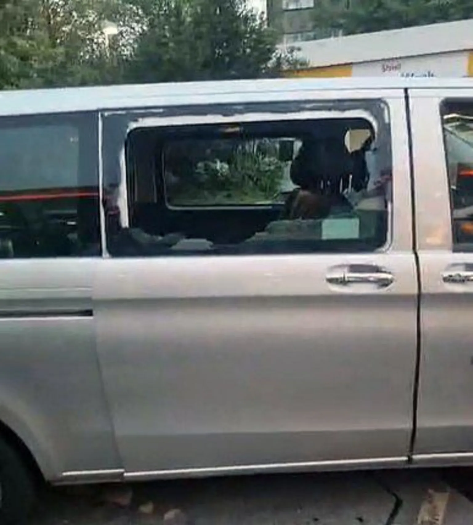 A side on view of a silver taxi with a smashed window