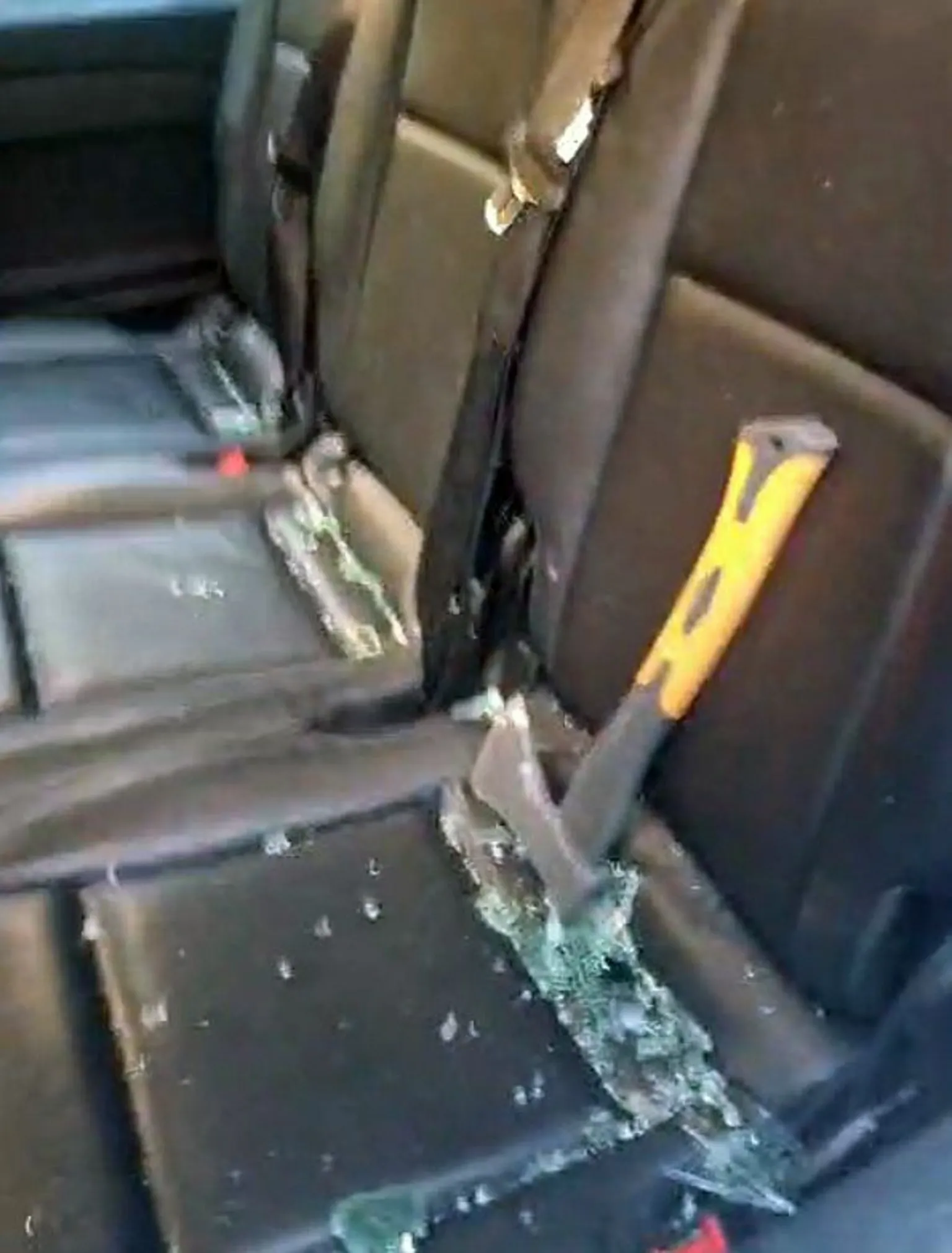 A yellow handled hand axe and broken glass on a vehicle seat