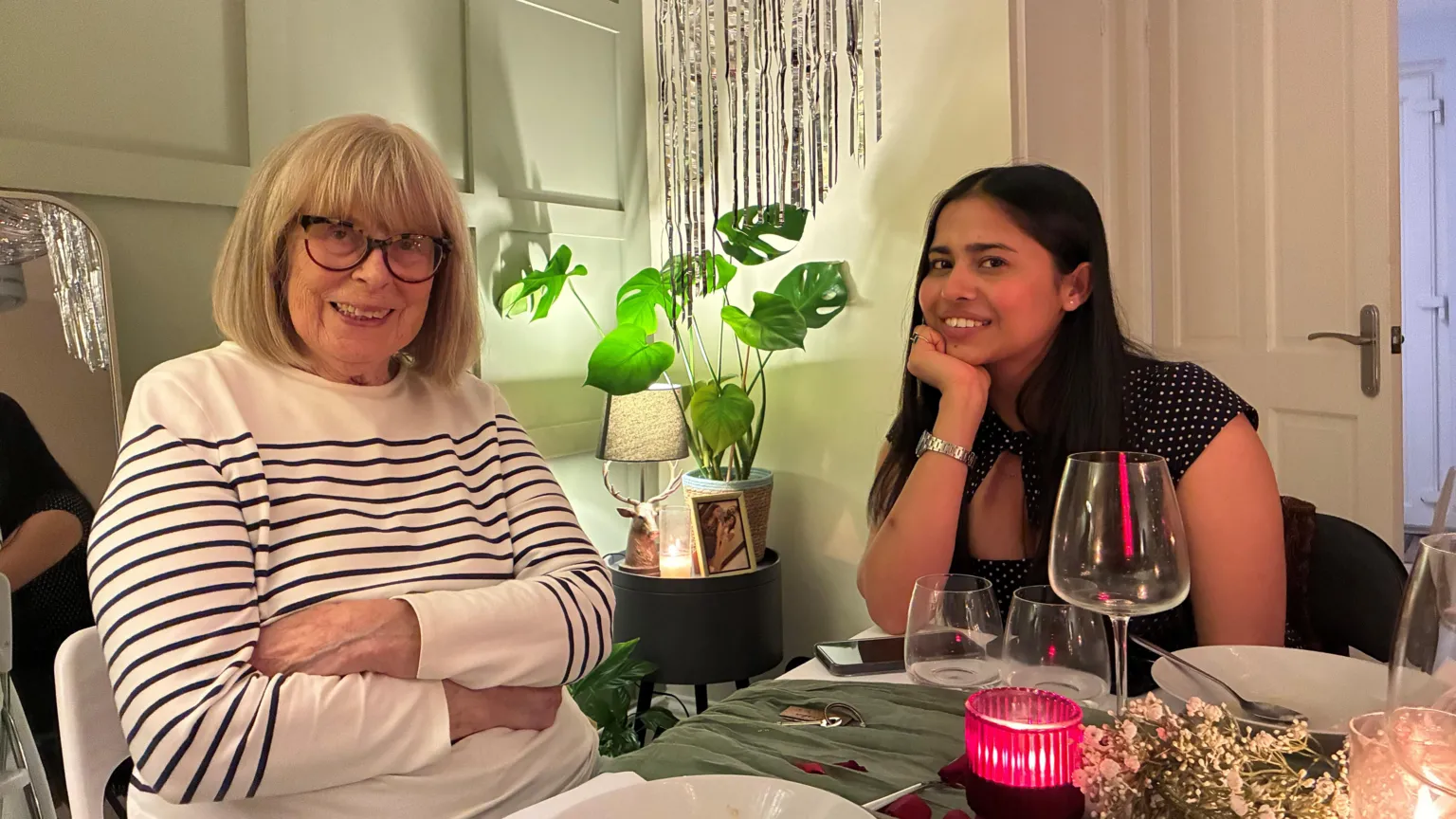 Two women are sitting at a table and smiling at the camera