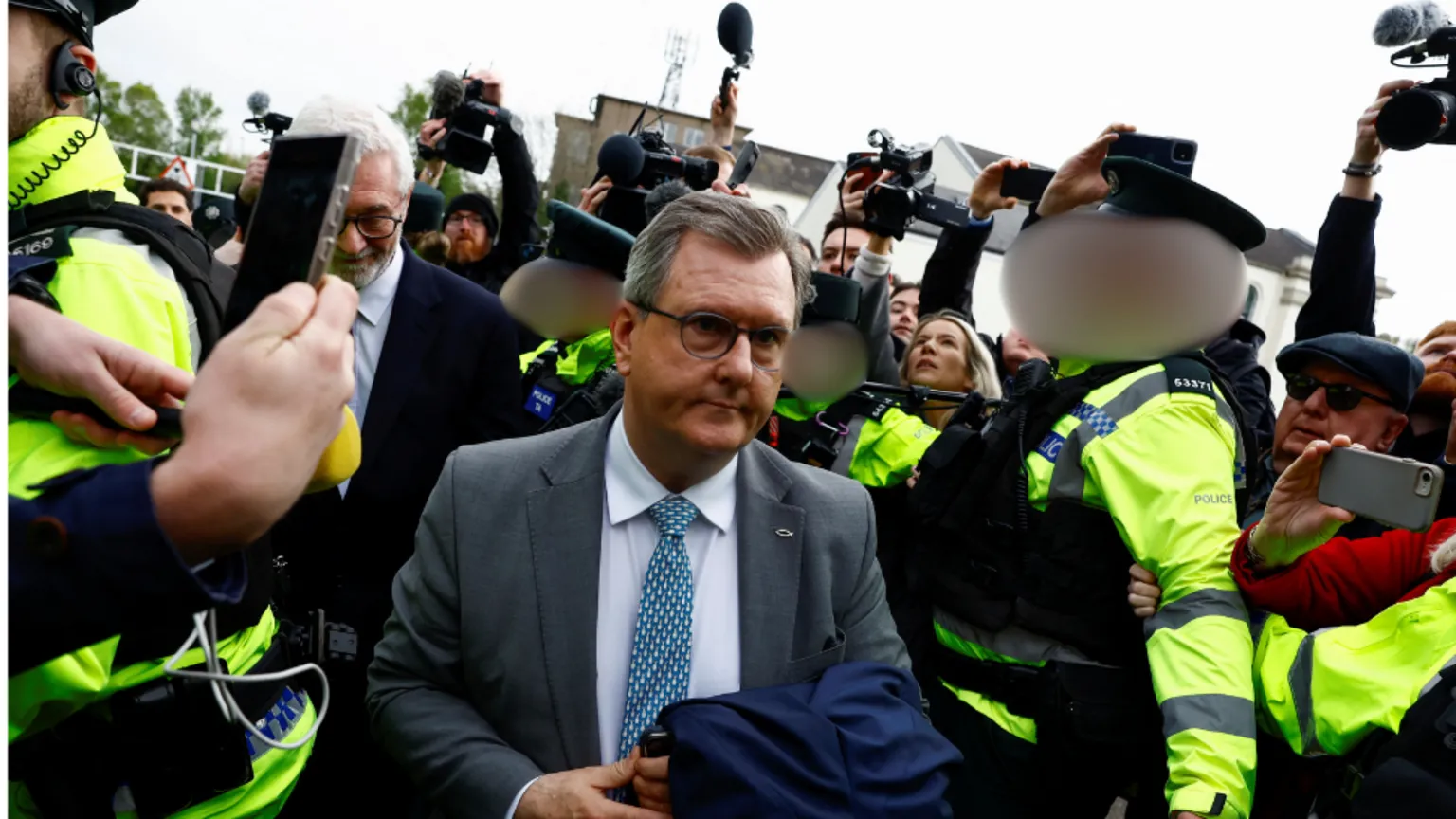 Jeffrey Donaldson arriving at court. A crowd of police officers and photographers are surrounding him.