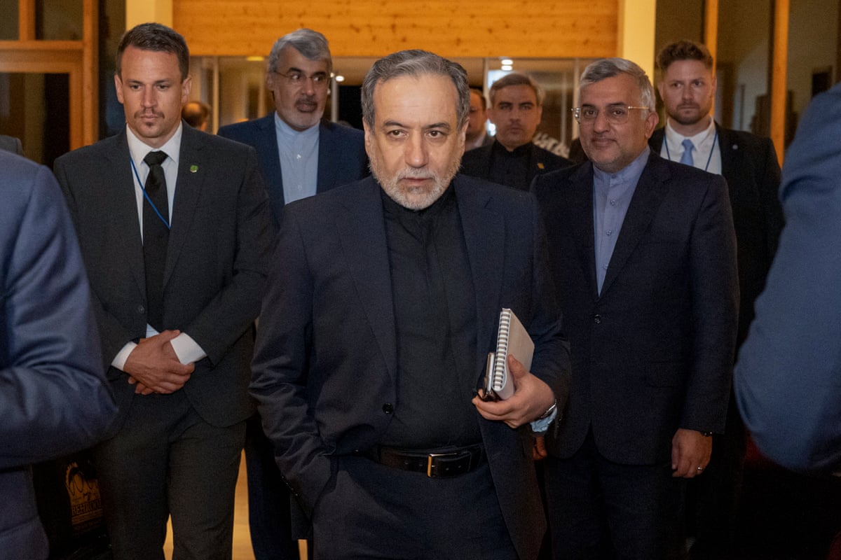 Abbas Araghchi walk down a corridor with the delegation behind him