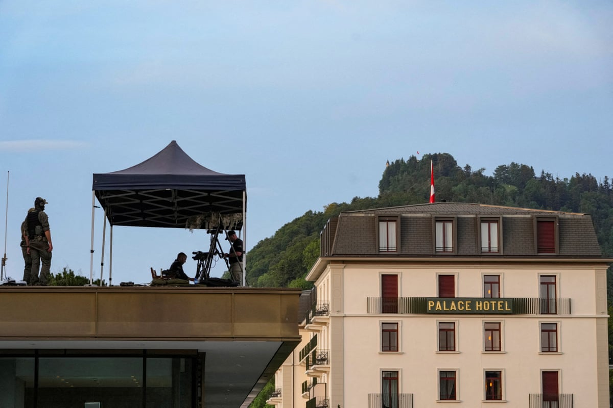 Four people in combat gear on a rooftop next to a hotel, two of them under a gazebo and two nearby