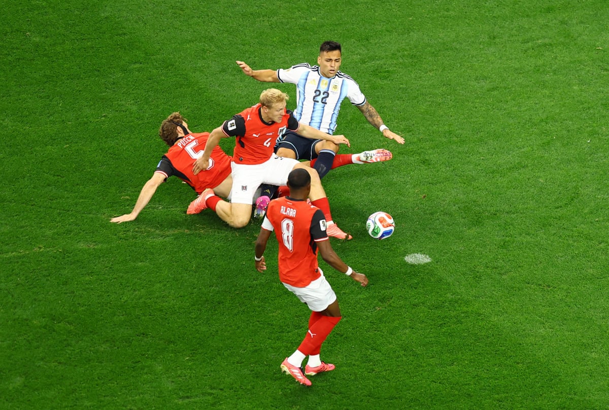 Argentina's Lautaro Martinez is fouled by Austria's Xaver Schlager and Stefan Posch resulting in a penalty.