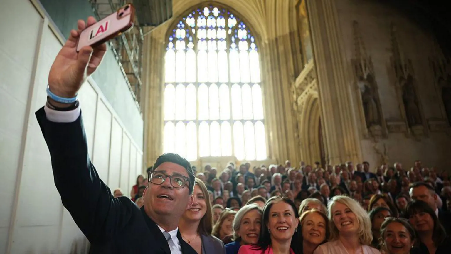 Andy Burnham holds his phone high to take a selfie of Labour MPs crowded behind on the stairs in Westminster Hall