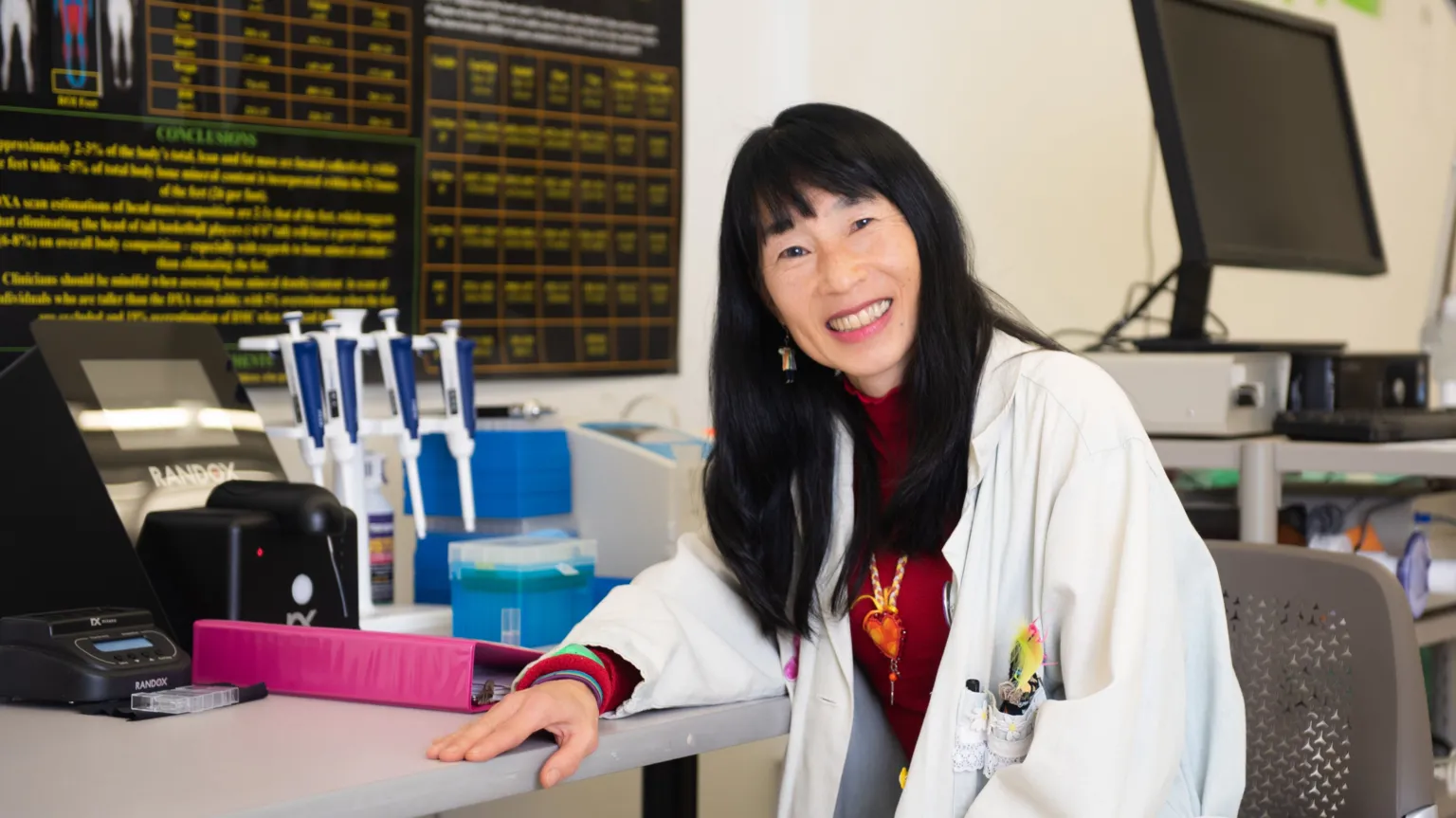 Wayne State University Wearing a lab coat, Tamara Hew-Butler sits at a desk in a laboratory.
