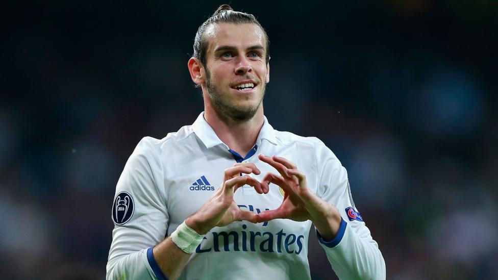 A smiling Gareth Bale playing for Real Madrid makes a heart gesture with his fingers