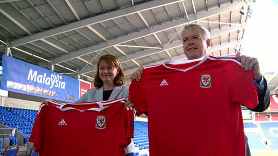 Llun o Leanne wood a Carwyn Jones gyda'i gilydd yn Stadiwm Dinas Caerdydd. Mae'r ddau yn dal crys tîm pêl-droed Cymru