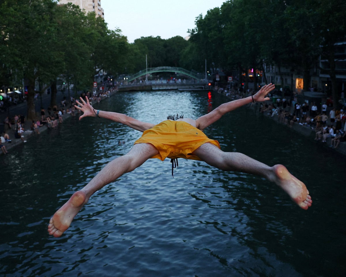 A man dives into the water in the Canal Saint-Martin as temperatures rise in Paris