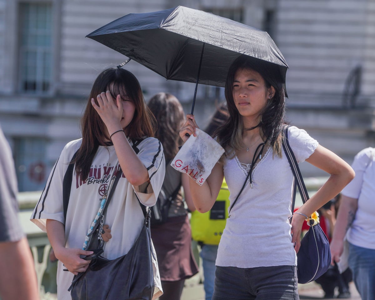 Tourists shelter under an umbrella at Westminster Bridge in London amid the extreme heat