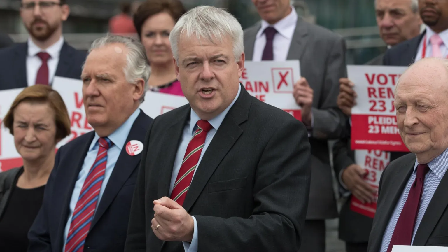 A group of Labour politicians campaigning, holding red Vote Remain 23 June banners. Carwyn Jones is stood in the middle of them, holding his left hand out and gesticulating.
