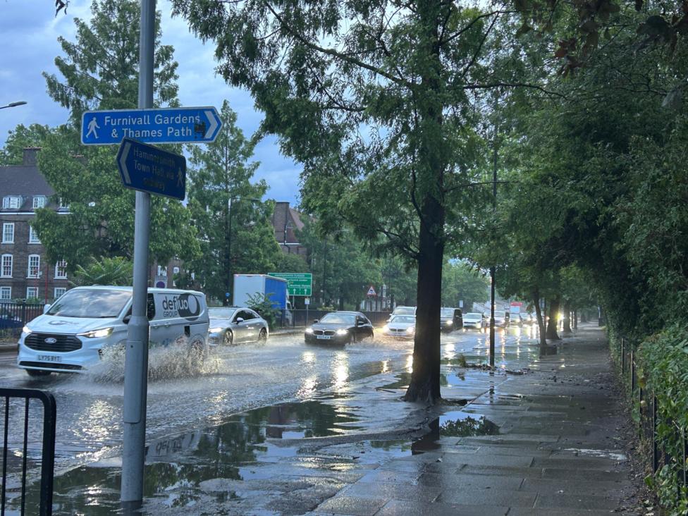 Cars drive through a flooded road in Hammersmith, London.