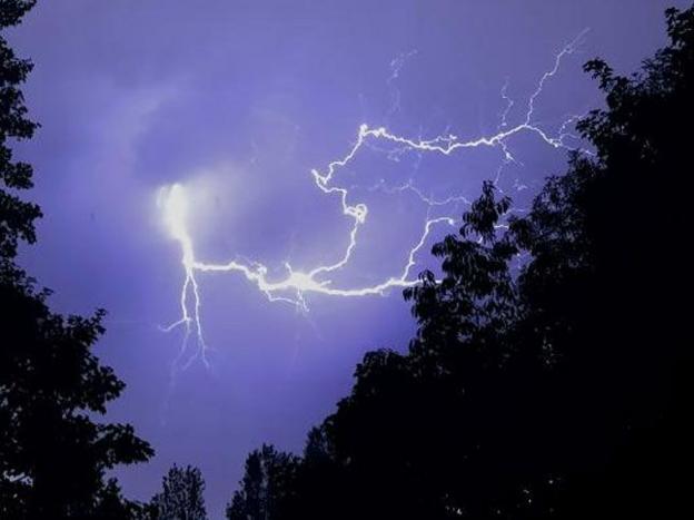 A bolt of Lightning pictured over a line of trees in Hornchurch, Greater London
