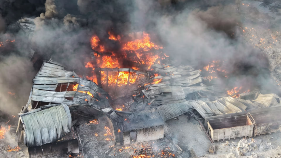 A badly fire-damaged building can be seen, with flames still burning and plumes of smoke in this aerial photo.