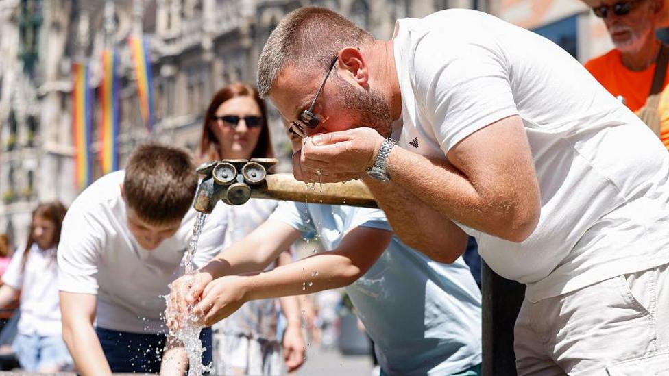 A man drinking from a water fountain in Munich