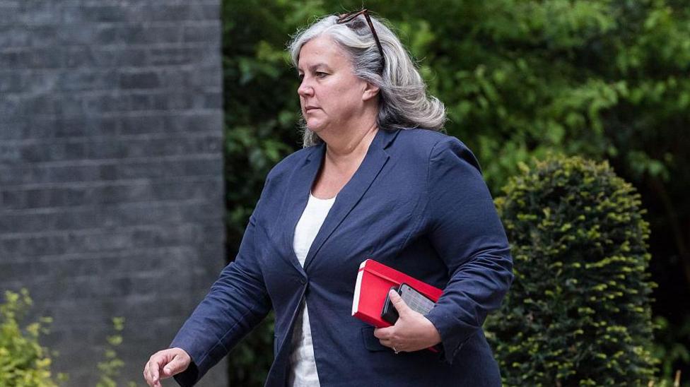 Secretary of State for Transport Heidi Alexander arrives in Downing Street to attend the weekly Cabinet meeting in London on 28 April 2026. She is wearing a white top and blue jacket and has a red notebook and phone in her hand, with sunglasses in her hair.