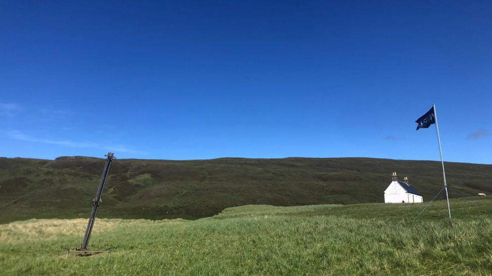 The area of the range is a large hilly and grassy area. There is a white-walled house and flag.