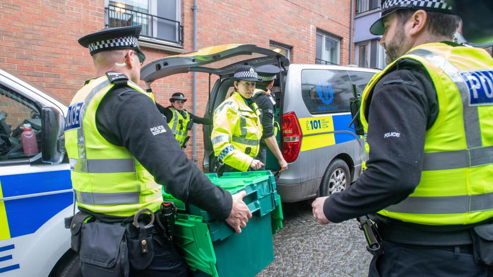 Police officers carrying green crates outside of Gordon Lamb House in Edinburgh.