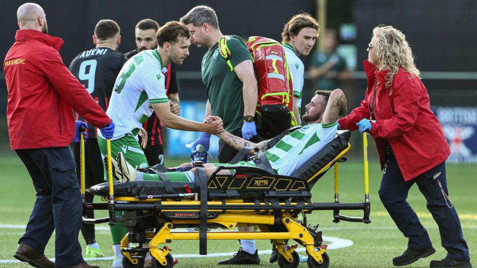 Leo Smith is consoled by New Saints team-mates as he is helped off