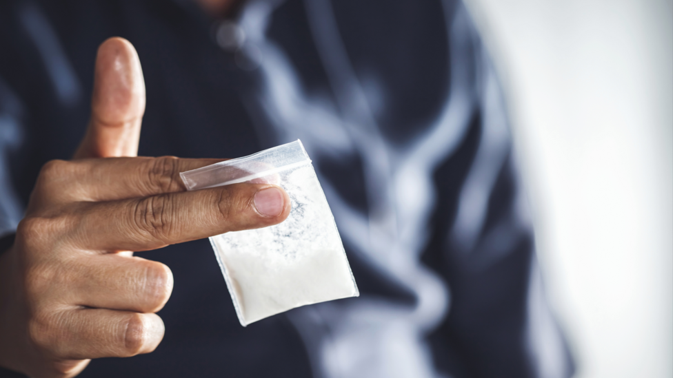 Man holding a bag of white powder in his hand.
