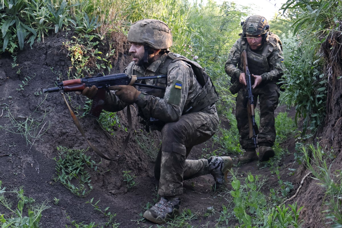 Two Ukrainian soldiers holding rifles in a trench
