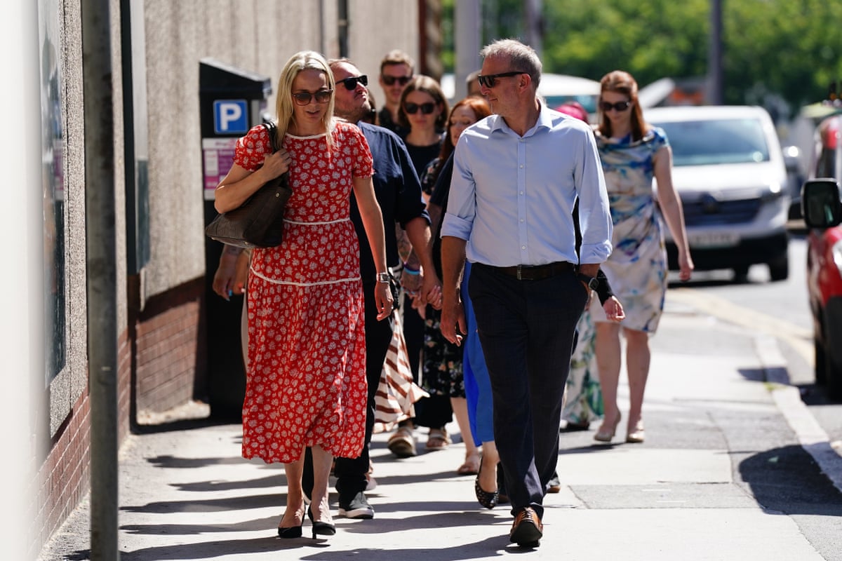 A couple walking in front of several others.