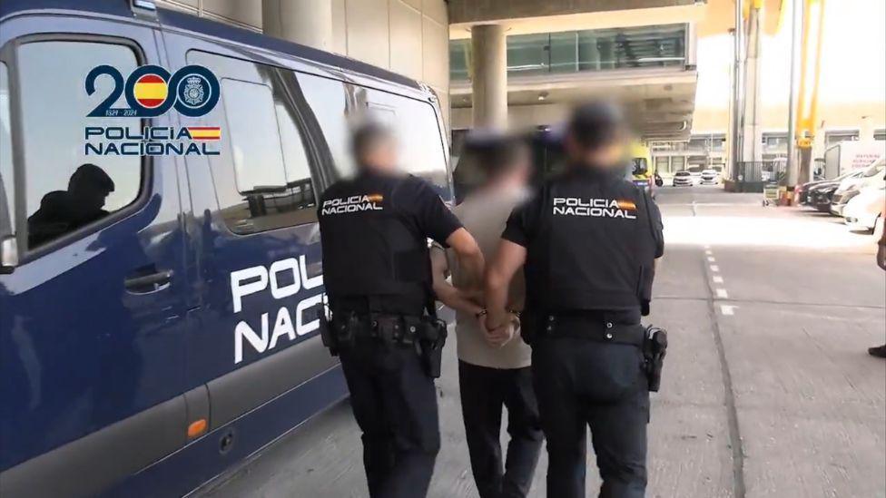Steven Lyons being taken into the back of a police van at Madrid Barajas Airport.