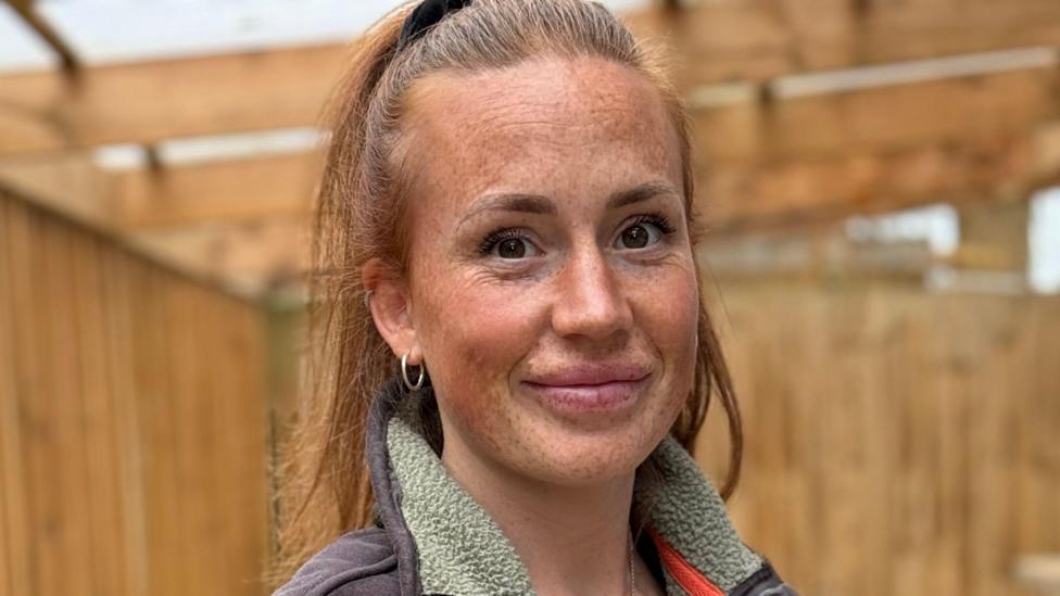 A woman wearing a blue and green fleece smiling at the camera.
