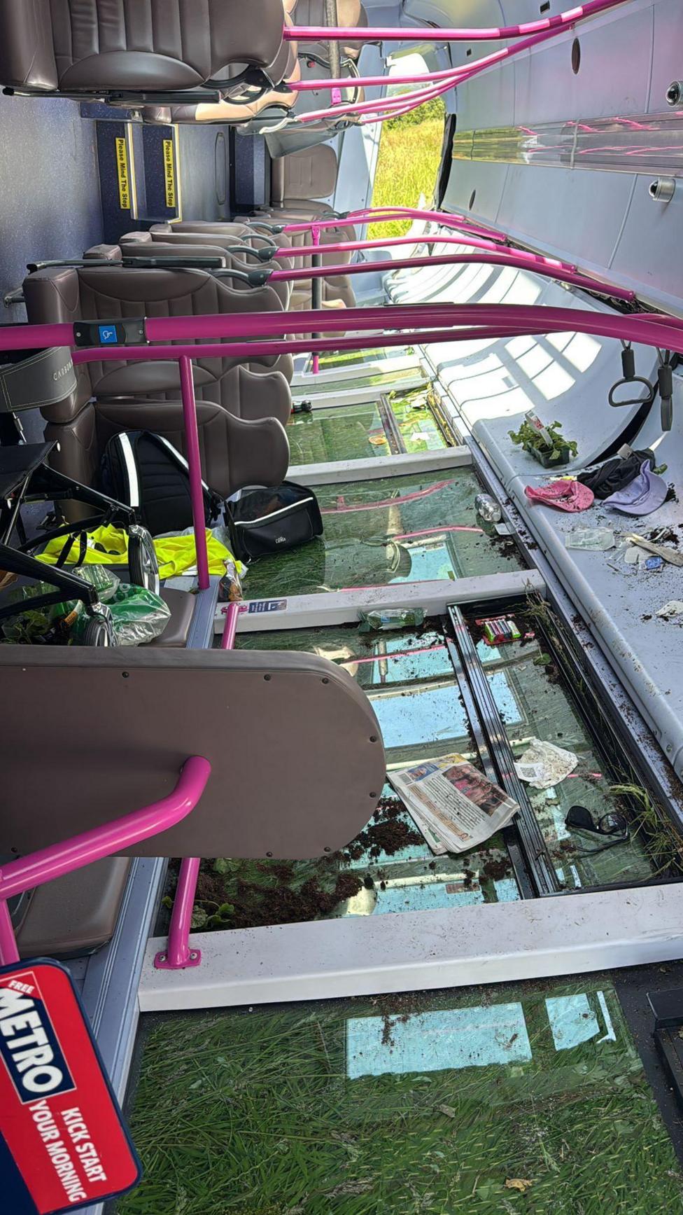 The inside of the crashed bus. The bus is empty and there are disability walkers left as well as debris on the smashed windows.