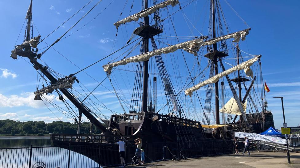 The Galeón Andalucía, a replica of a Spanish 18th century boat is morred on a quay. It is a tall ship type vessel with high masts and big sails