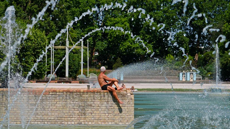 A man sunbathes next to the water in Battersea park
