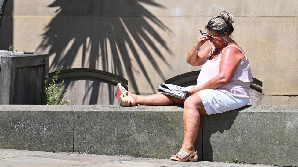 A crossword is worked on in the sunshine in the town centre in Huddersfield in Northern England on June 23, 2026, as temperatures increase to heatwave levels and are set to rise further in the week ahead. 