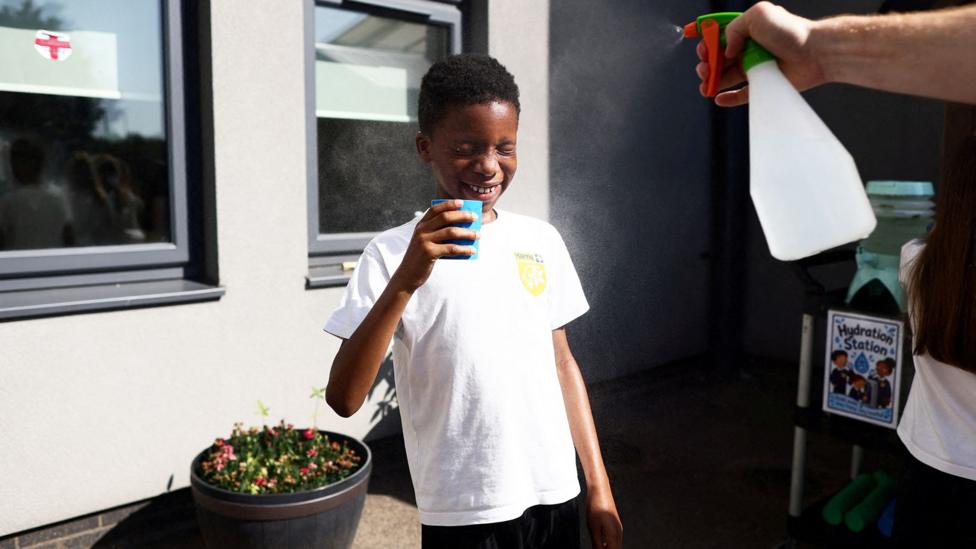 A pupil is sprayed with a fine mist as they drink water at the Harris Academy Primary Maxyflower school, as Britain experiences record temperatures disrupting schools and transport networks, in Grays, Britain, June 24, 2026. 