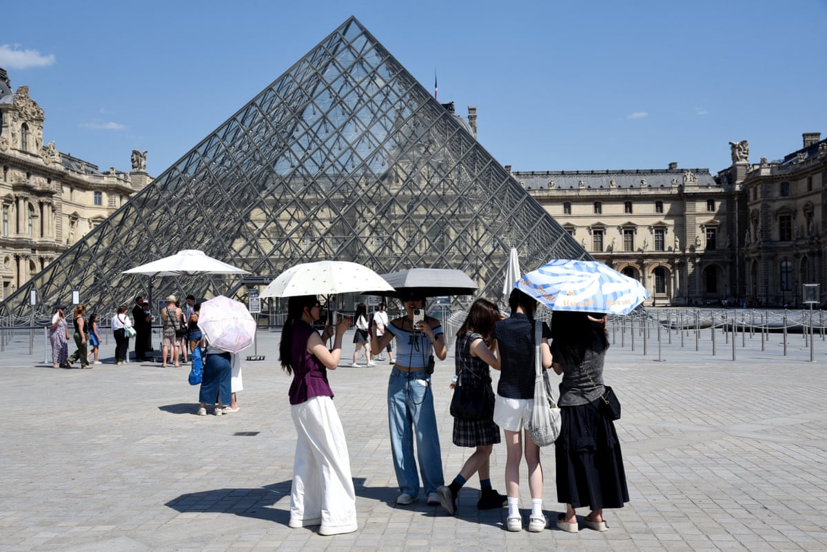 People outside the Louvre in Paris shade themselves with umbrellas