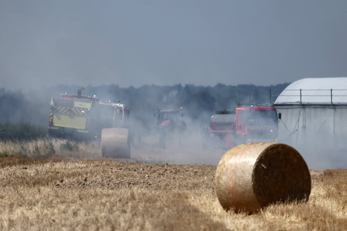 French firefighters work to extinguish burning haystacks in a field