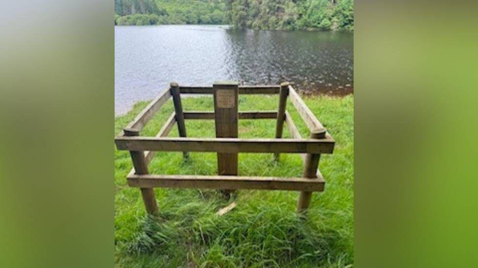 A wooden pallet and a wooden stick next to some water 