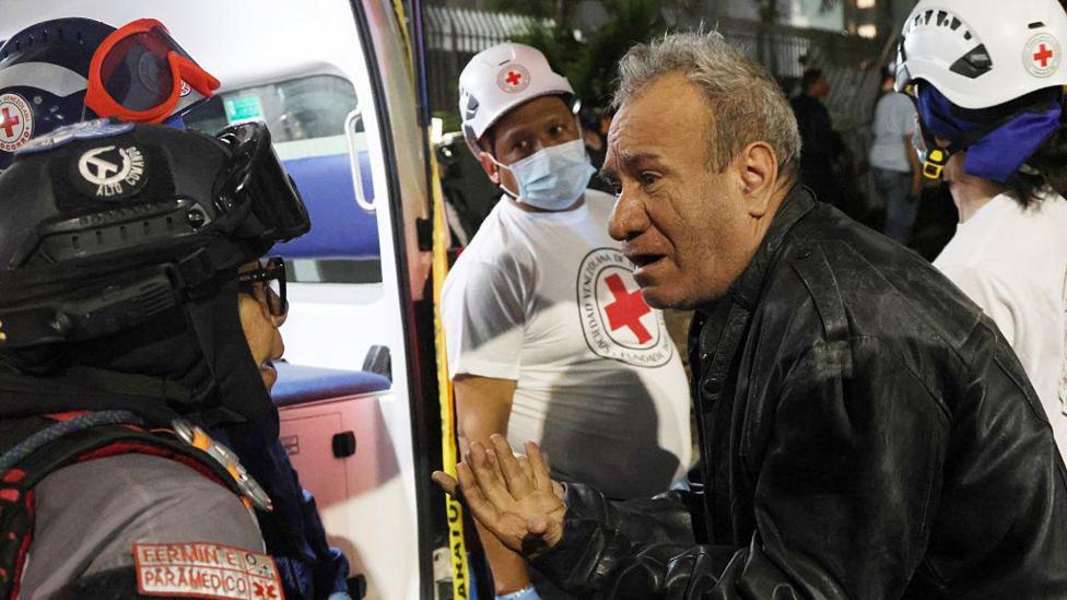 A man speaks to a paramedic in a demolished building at Los Palos Grandes after a magnitude 7.2 earthquake struck Venezuela and other regions in the Caribbean on June 24, 2026 in Caracas, Venezuela. 