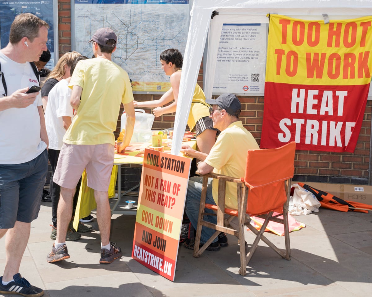 People sitting or standing around a table near a banner reading 'Too hot to work'