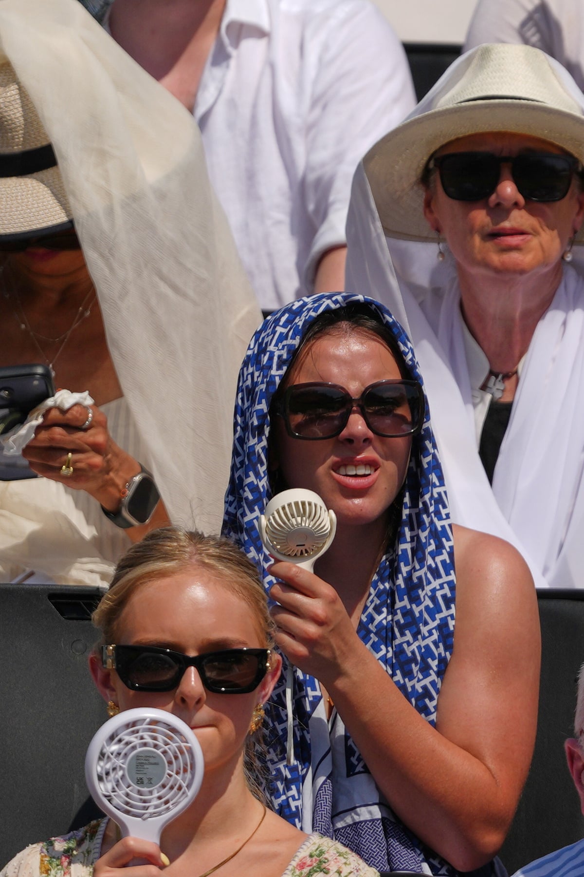 People use fans against the heat at a tennis match in London