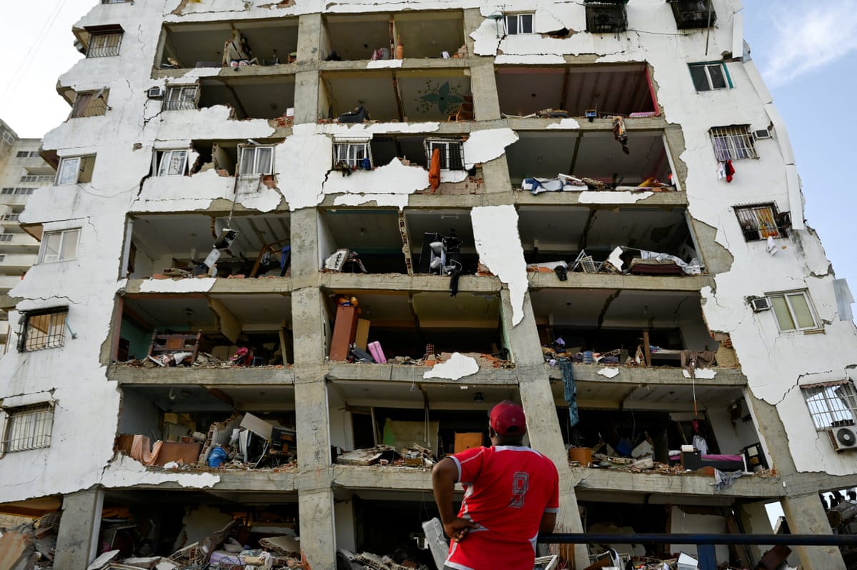 A man looks at a damaged high-rise building in the aftermath of earthquakes in La Guaira.