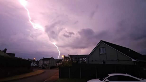 Shows a bolt of lightning with houses in the foreground