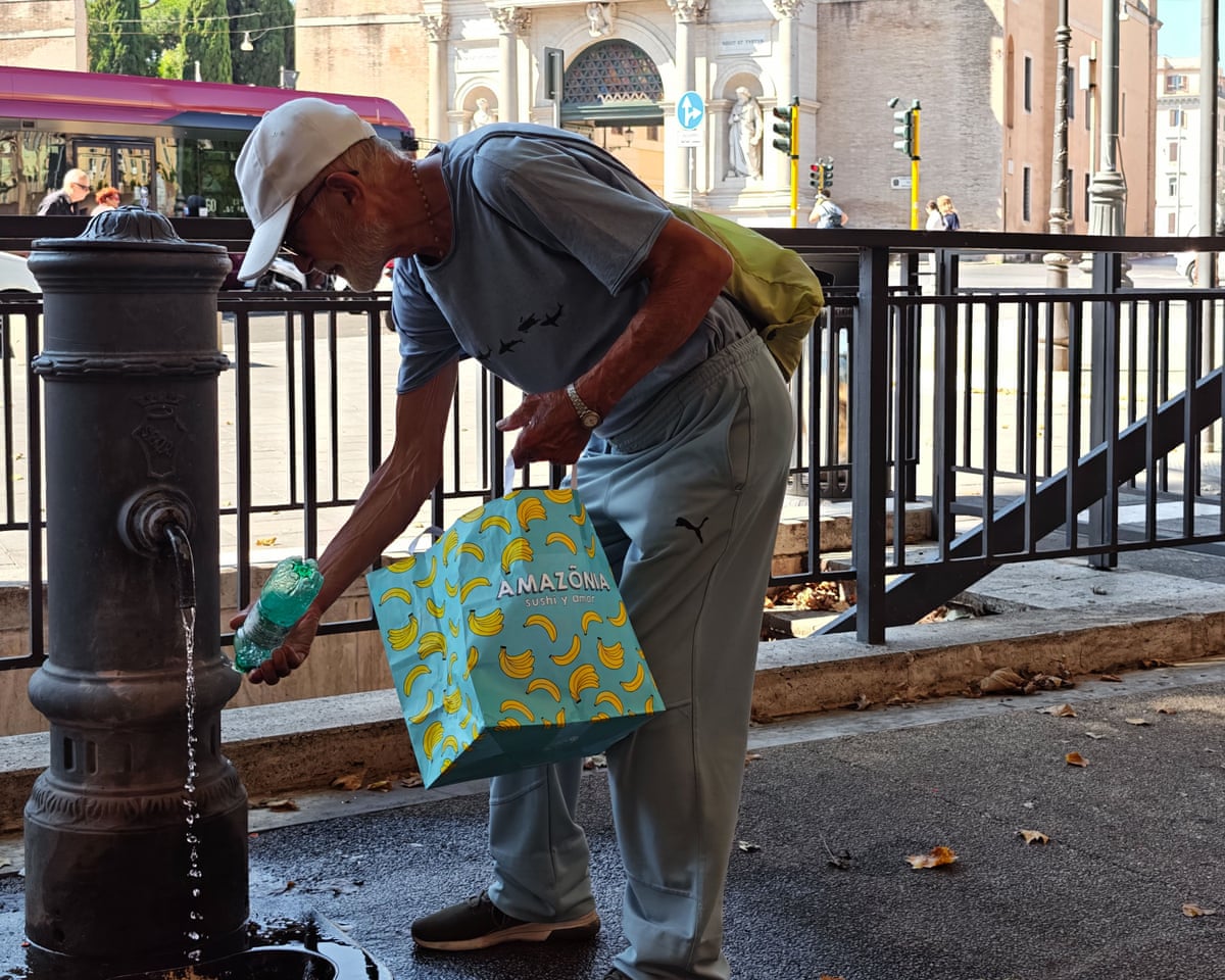 A senior refills a reusable water bottle at a public drinking fountain in Rome, Italy.