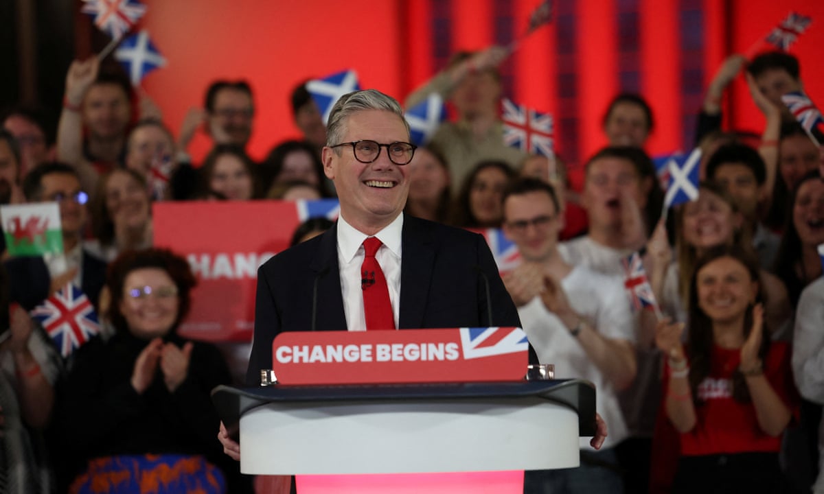A smiling Keir Starmer standing at a lectern with branding on it reading 'Change begins'