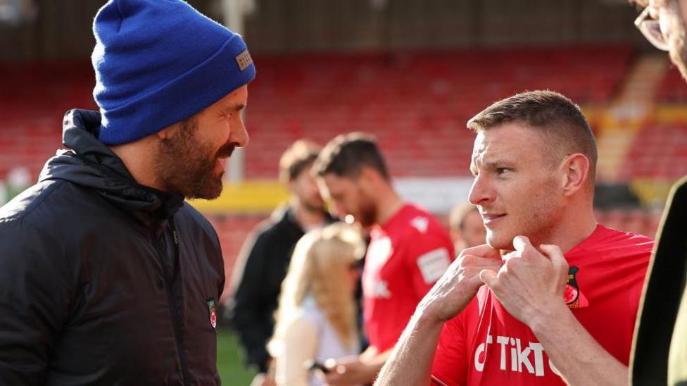 Ryan Reynolds (left) chats with Paul Mullin on the pitch following a game