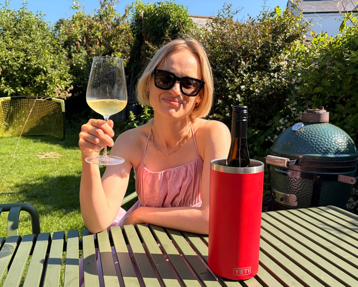 Mina Holland seated at a garden table raising a glass of wine with the Yeti Rambler wine cooler.