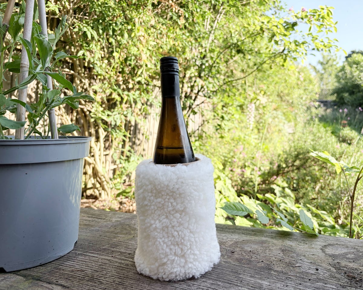 A bottle of wine in the Dartmoor Shepherd sheepskin wine cooler on a garden table.