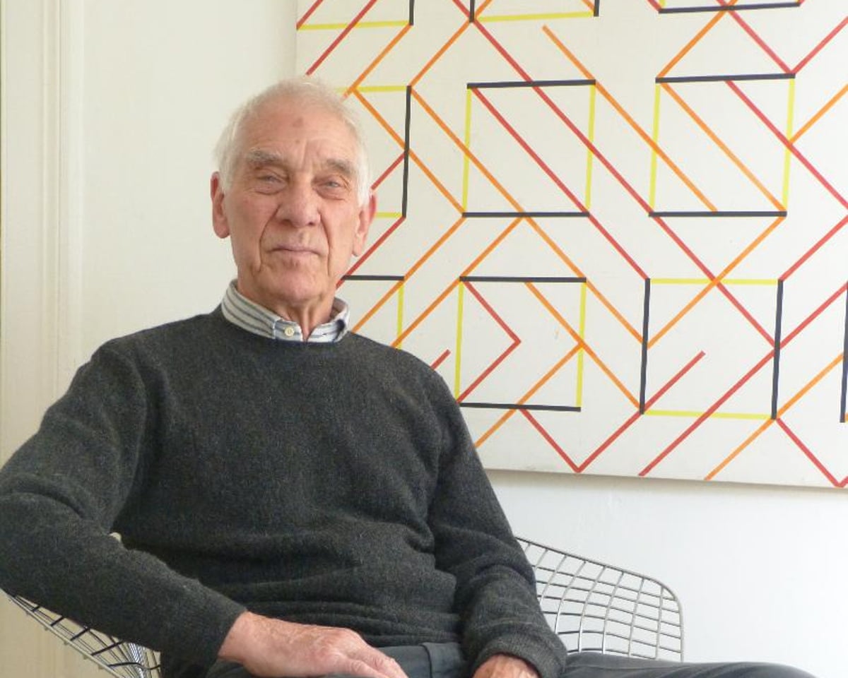 Peter Ahrends sitting in front of a geometric design on the wall