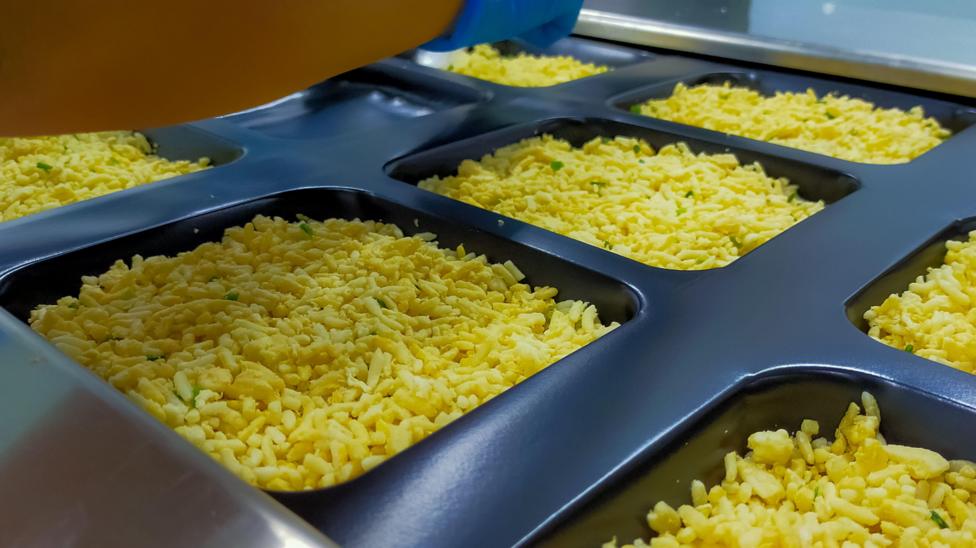 Frozen fried rice with egg in plastic tray waiting for top seal label