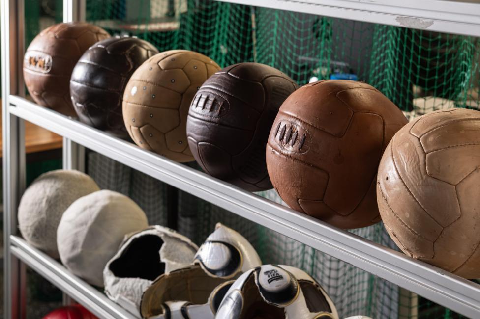 A line of leather footballs lined up on a rail