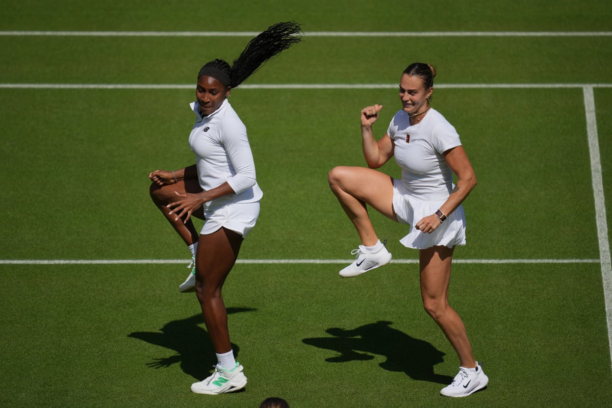 Gauff on the left and Sabalenka on the right, dressed in tennis whites, dancing with their right knees bent up high